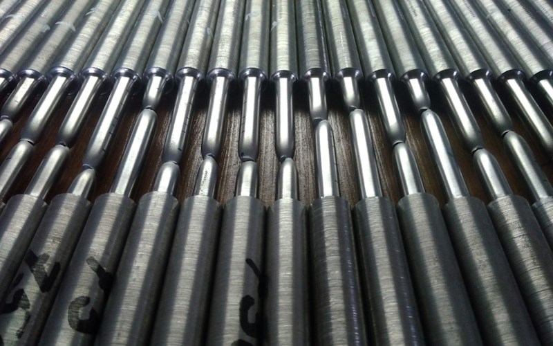 Steel tensile test specimens arranged on a work surface for mechanical testing and stress-strain measurement.