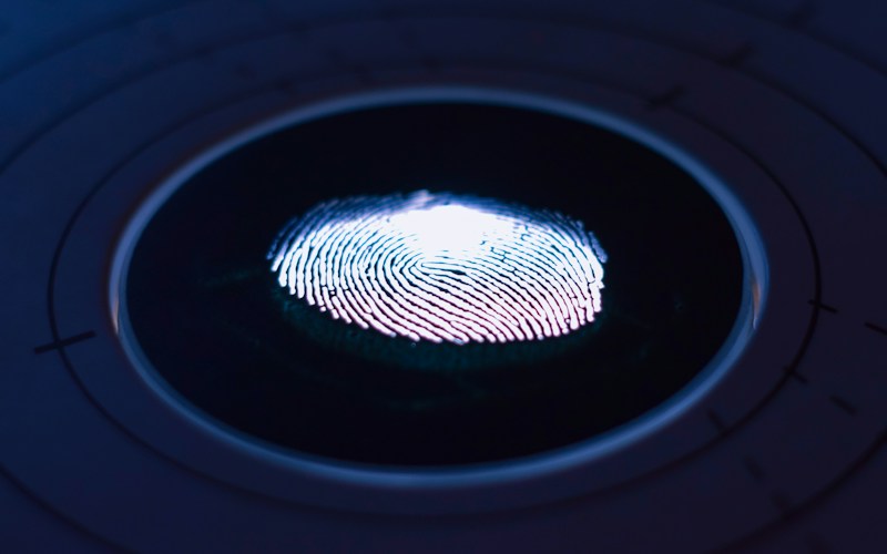 Close-up of a fingerprint illuminated on a circular scanner, illustrating forensic evidence examination.