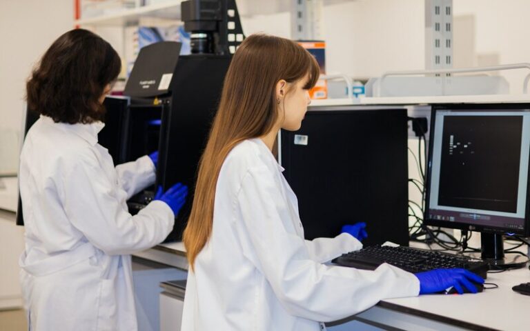 Two laboratory scientists review imaging data at computer workstations.
