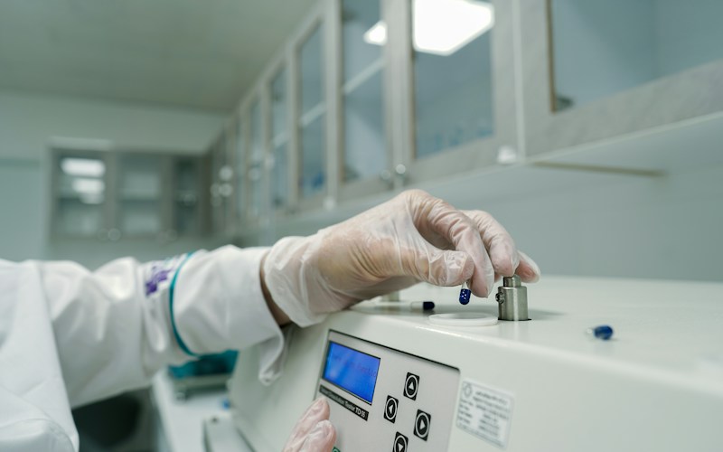 A gloved laboratory analyst adjusts a small sample holder on a benchtop instrument.